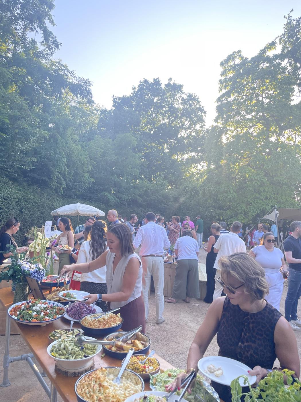 Guests helping themselves to a garden party buffet of salads and sides under the trees